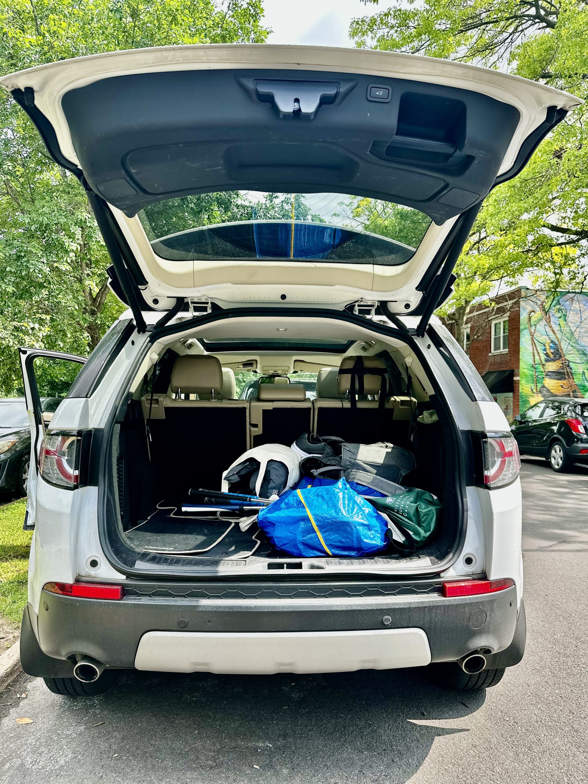 A white Land Rover Discovery Sport with it's trunk open; shown from the back of the car.